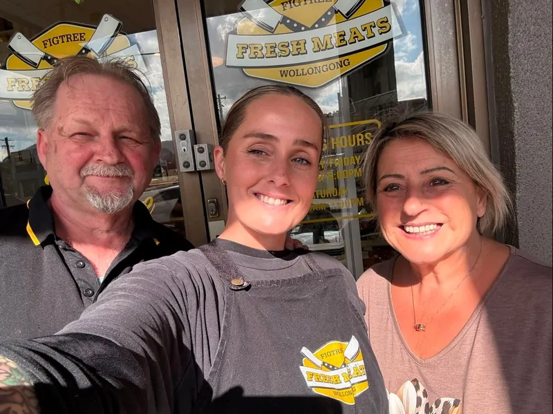 Steve and Gracie with their daughter Jessie at the door of Figtree Fresh Meats, under the badge on the glass