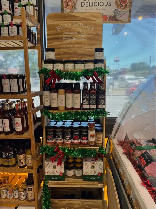 Pantry shelves in the shop at Christmas: sauces, rubs, relishes and Christmas cakes with tinsel